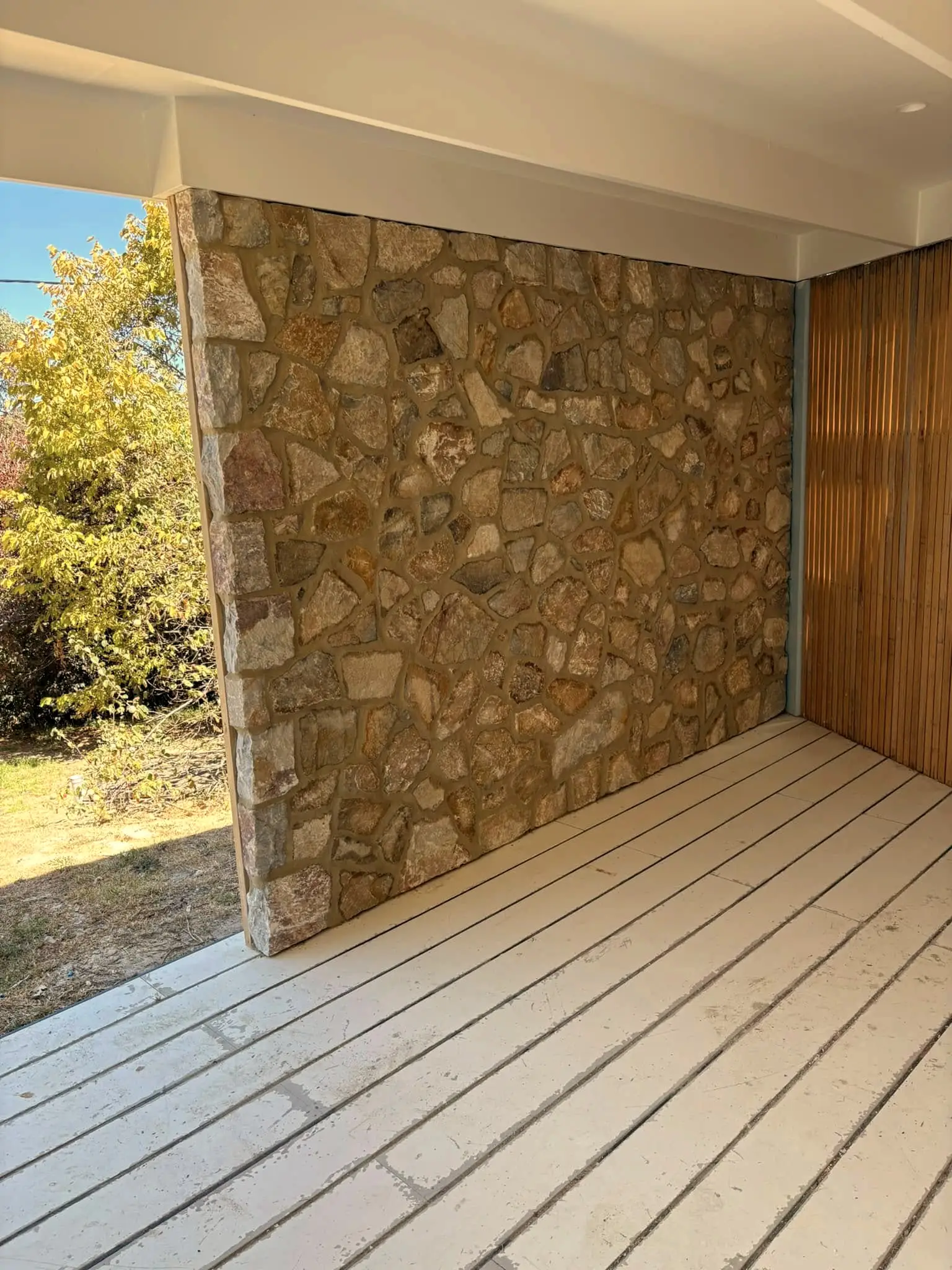 A freestanding sandstone feature wall on a timber deck, framed by vertical battens.